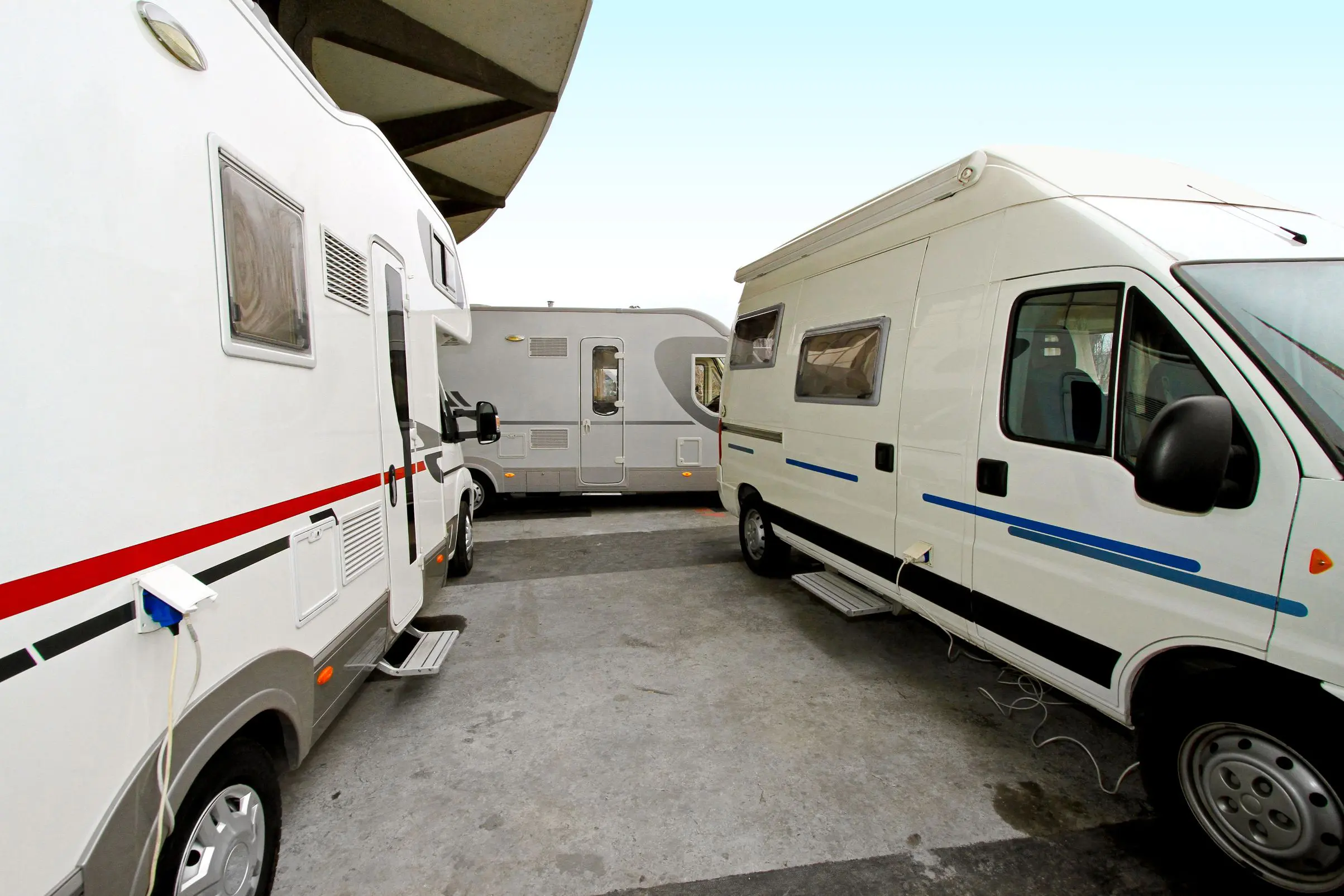 Three parked motorhomes in a lot.