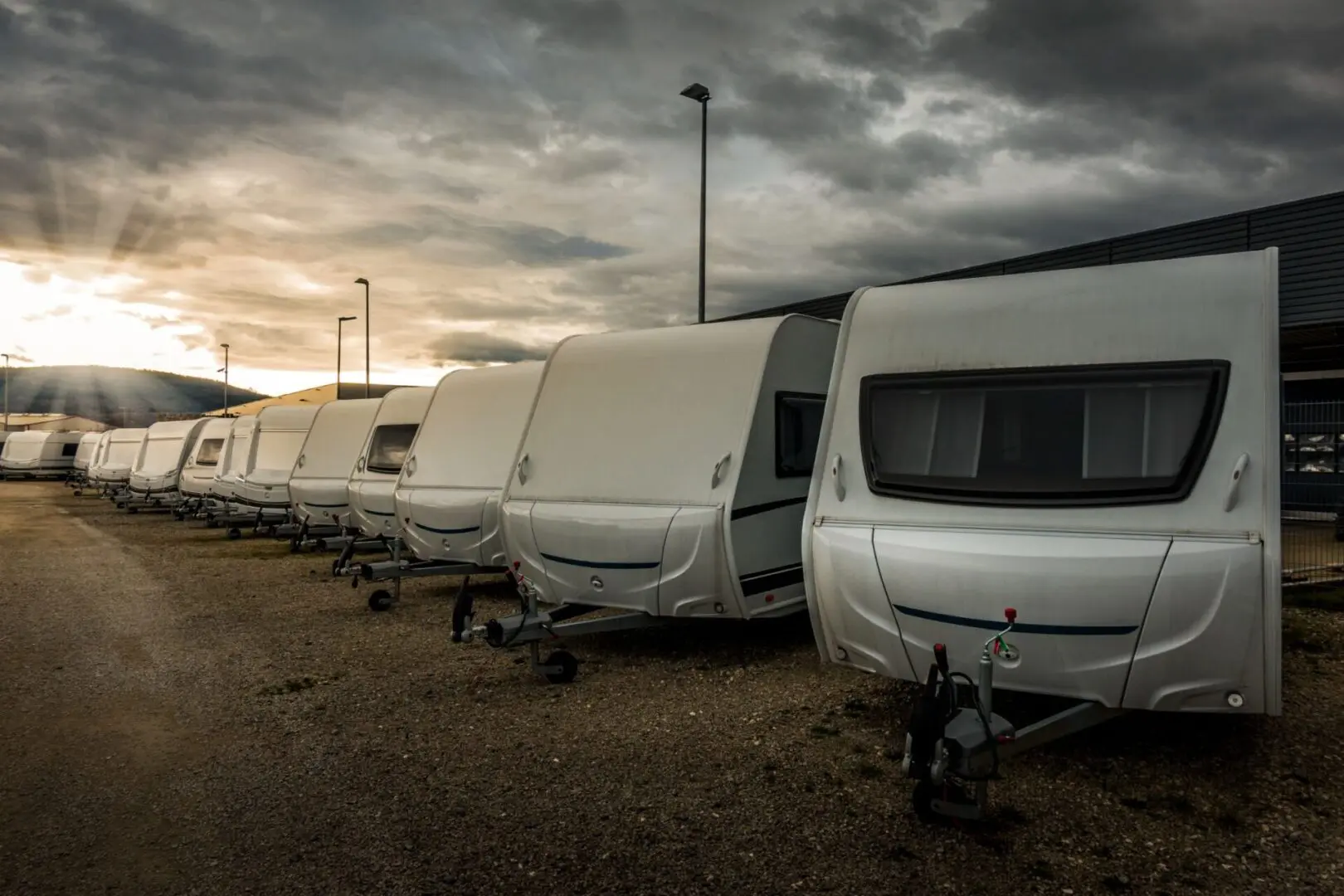 Row of parked caravans under cloudy sky.
