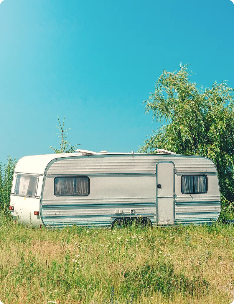 White camper trailer in grassy field.